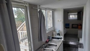A compact kitchen with a stainless steel sink, a coffee maker, and a window. - Apartment with pool and garden (Boisset-et-Gaujac)
