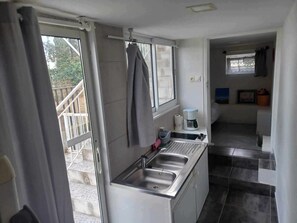 A compact kitchen with a stainless steel sink, a coffee maker, and a window. - Apartment with pool and garden (Boisset-et-Gaujac)