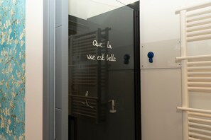 A bathroom with a frosted glass door, a towel rack, and a wall with a floral pattern.
