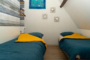 Un dormitori amb dos llits, una paret de fusta i un quadre.