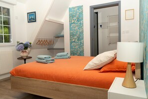Et soveværelse med en seng, et natbord, en lampe, en radiator, et vindue, en dør og en væg med blomstermønster.