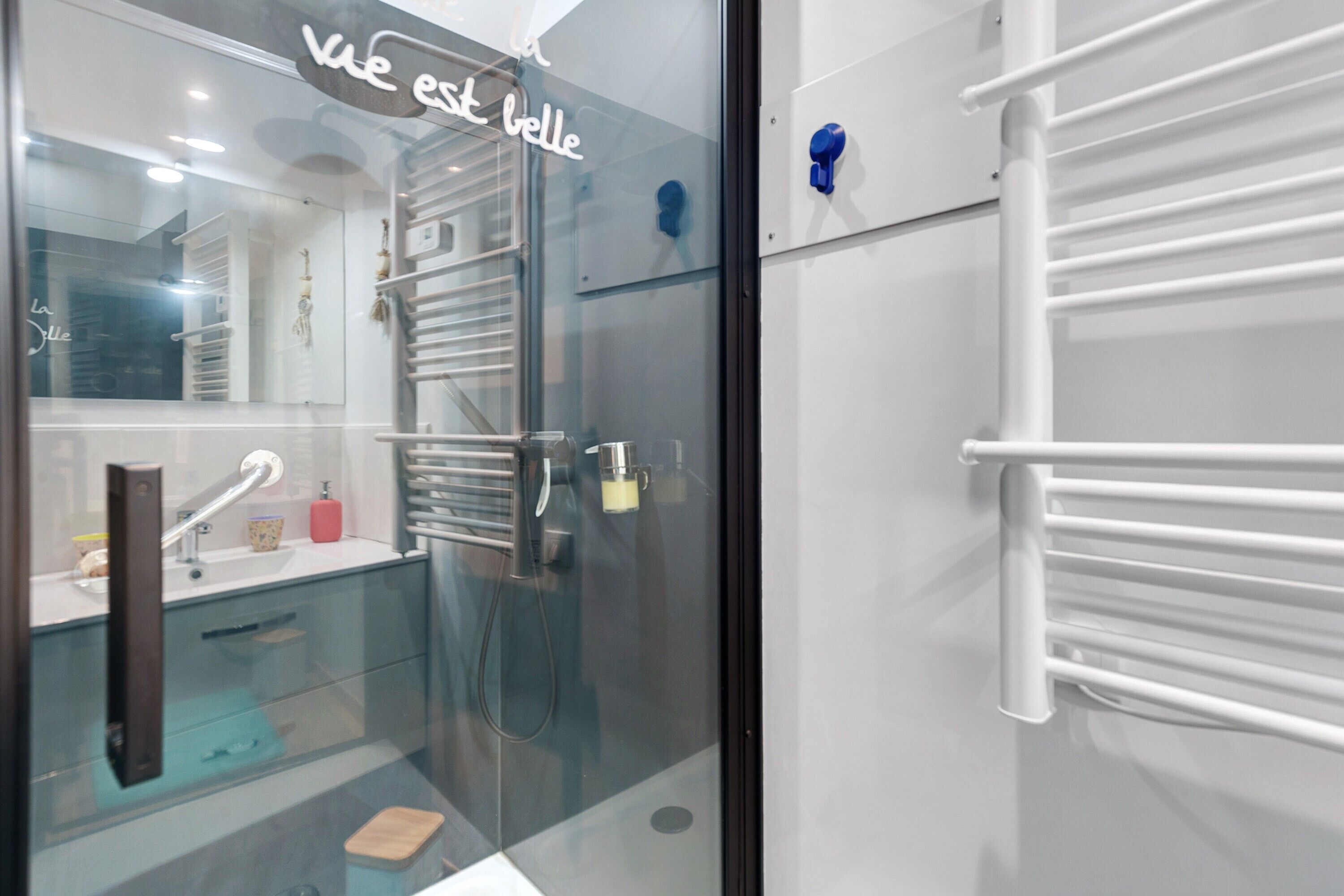 Une salle de bain moderne avec une douche à parois de verre, un lavabo blanc et un porte-serviettes.