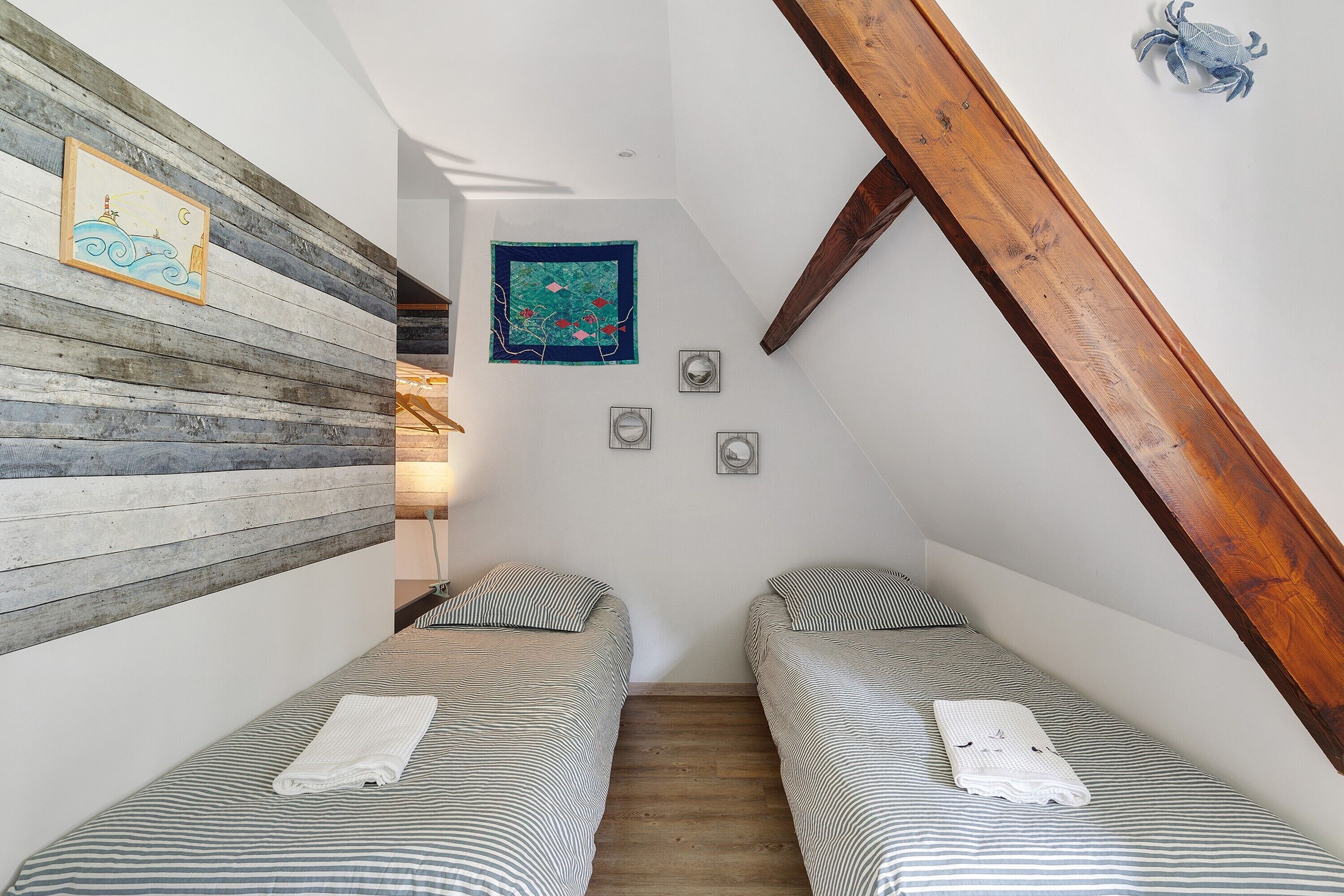 Una stanza piccola e stretta con due letti singoli, un pannello di legno a doghe e un soffitto con travi in legno.
