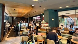 A modern cafe with seating, a counter, and a view of the street. - Pandora’s Nest, Makati ,1BR MRT-Connected Home, Rooftop pool,  Long Stay- ready (Makati City)