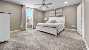 Un dormitorio con cama, ventilador de techo, ventana con cortinas y radiador.