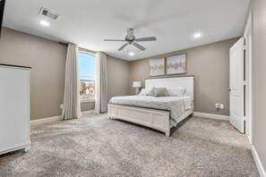 A bedroom with a bed, a ceiling fan, a window with curtains, and a radiator. - 3-Bedroom Townhome - The Gardens Cottage Duo Unit A (Houston)