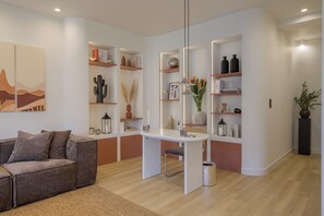 A modern living room with a sofa, a dining table, and built-in shelving with decorative items. - Sunny Central Retreat with Private Plunge Pool (Athina)