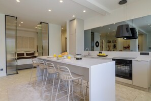 A modern kitchen with a central island, bar stools, a dishwasher, and a large mirror. - Sunny Central Retreat with Private Plunge Pool (Athina)