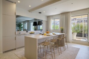 A modern kitchen with a central island, bar stools, and a large window with curtains. - Sunny Central Retreat with Private Plunge Pool (Athina)