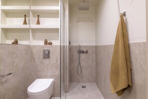 A modern bathroom with a glass-enclosed shower, a toilet, and shelves with decorative vases. - Sunny Central Retreat with Private Plunge Pool (Athina)