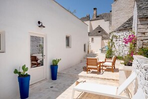 Un edificio blanco con una puerta, una ventana y un pequeño balcón con mesa y sillas.