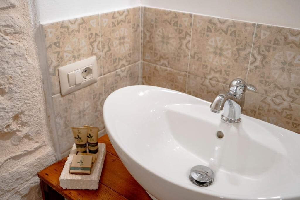 A bathroom with a white sink, a towel, and a small bottle on a wooden surface.