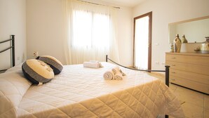 Ein Schlafzimmer mit Bett, Kommode, Spiegel und einem Fenster mit Vorhängen.