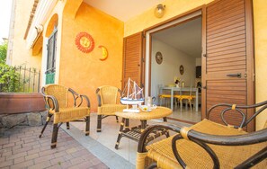 An outdoor seating area with wicker furniture, a small table, and a decorative sailboat model. - Casa delle Sorgenti 1 (Torpè)