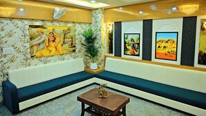 A modern living room with a sectional sofa, a coffee table, and wall-mounted artwork. - Gehlot Paradise Hotel (Nagaur)