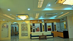 A lobby with a seating area, decorative panels, and a reception desk. - Gehlot Paradise Hotel (Nagaur)