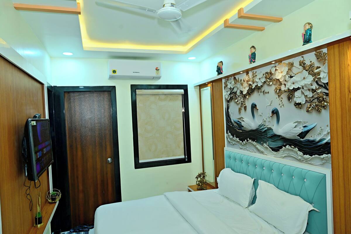 A hotel room with a bed, a TV, a ceiling fan, a wall-mounted air conditioner, and a decorative wall with a seagull mural.