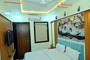 Une chambre d’hôtel équipée d’un lit, d’une télévision, d’un ventilateur de plafond, d’un climatiseur mural et d’un mur décoratif orné d’une fresque représentant une mouette.