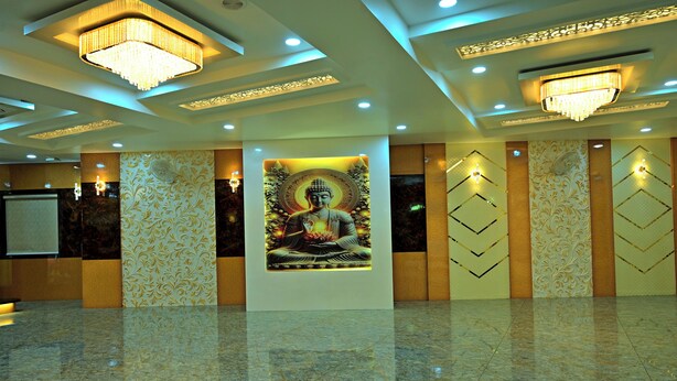 A spacious lobby with a large Buddha statue, chandeliers, patterned walls, and a polished marble floor. - Gehlot Paradise Hotel (Nagaur)