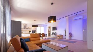 A modern living room with a sofa, coffee table, and a dining area with chairs. - Family house with pool (Divsici)