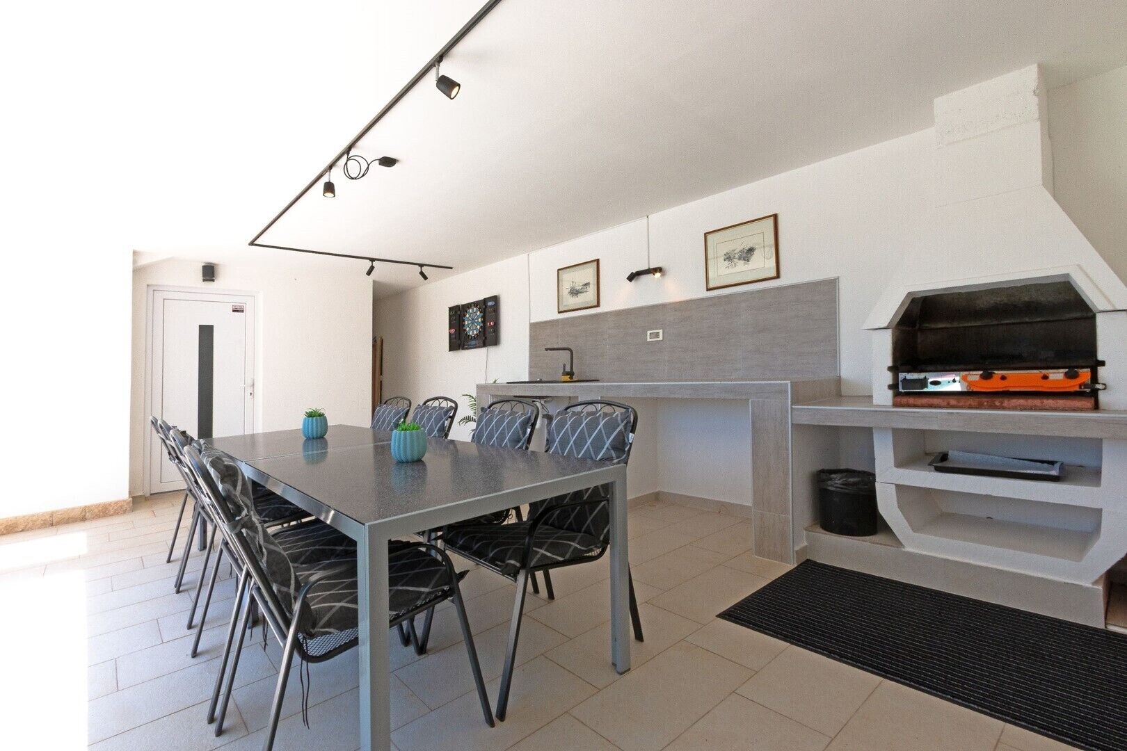 Una cocina moderna con una mesa de comedor, sillas, una parrilla y cuadros en la pared.