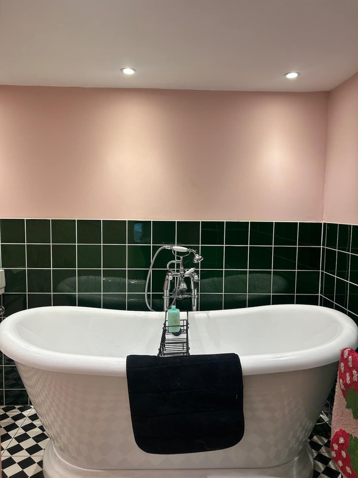 Een badkamer met een vrijstaand bad, een douche en een betegelde wand.