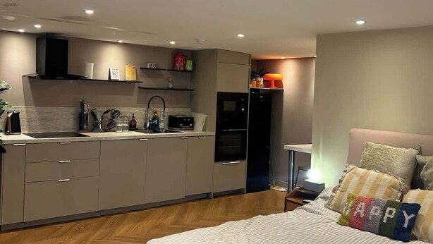 Un dormitorio moderno con una cama grande, una mesita de noche y otra mesita auxiliar.
