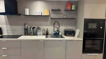A modern kitchen with a built-in oven, a sink, and a countertop with various kitchen items.