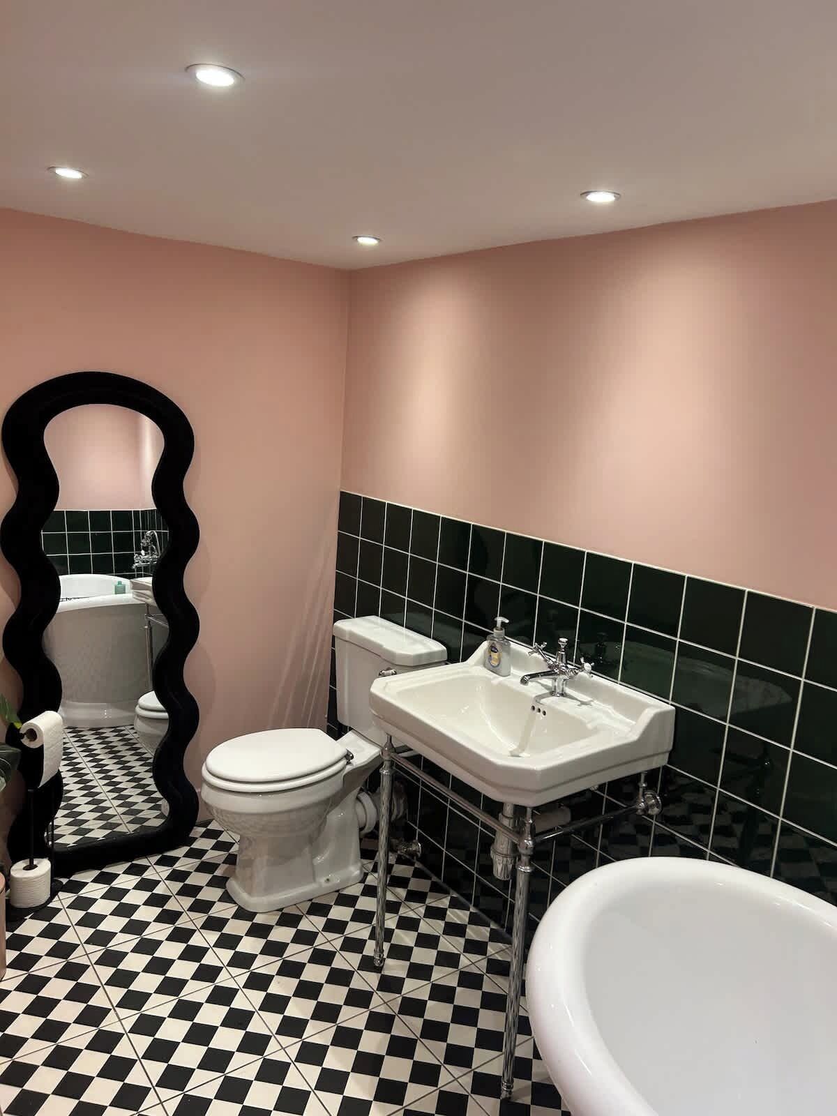 A bathroom with a black and white checkered floor, a white toilet, a white sink, and a bathtub.