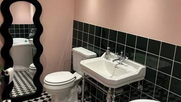 A bathroom with a black and white checkered floor, a white toilet, a white sink, and a bathtub.