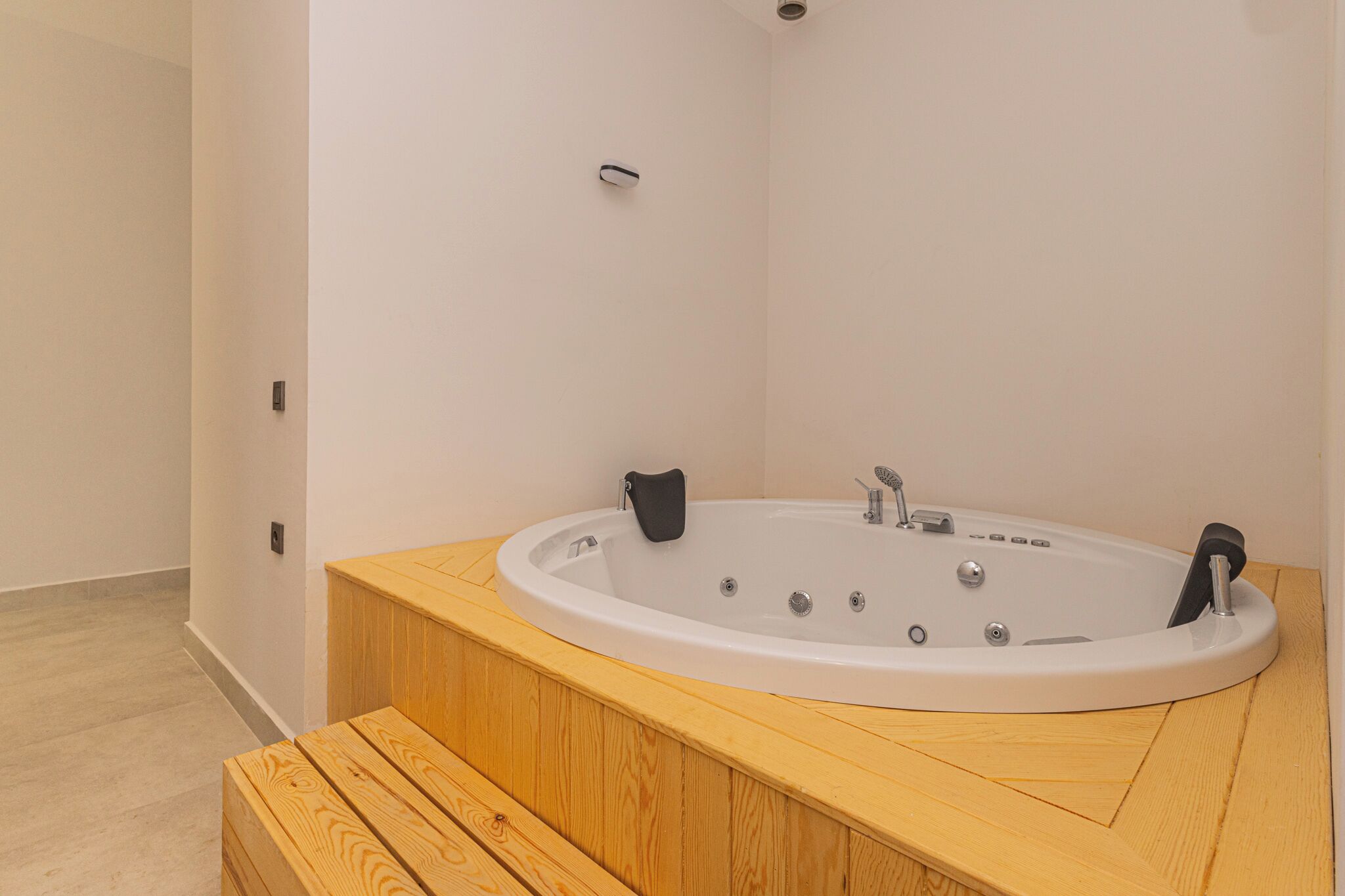 A modern bathroom with a freestanding bathtub, wooden vanity, and a bench.