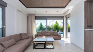 Una sala de estar moderna con un sofá, una mesita de centro y vistas a una piscina.