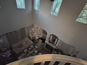 Una habitación con techos altos, un candelabro, una chimenea y vistas a través de una ventana.
