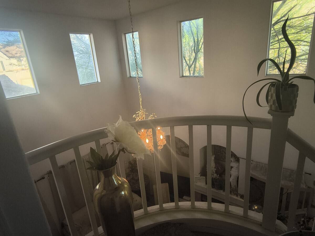 A room with a white railing, a chandelier, and a potted plant.