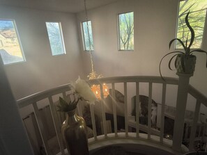 A room with a white railing, a chandelier, and a potted plant. - Cozy and classy, comfortable bed close to strip (Las Vegas)