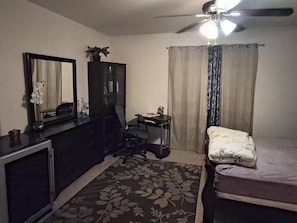A bedroom with a bed, a desk, a chair, a ceiling fan, and a window with curtains. - 1-bedroom bed & breakfast in delightful Las Vegas with AC (Las Vegas)