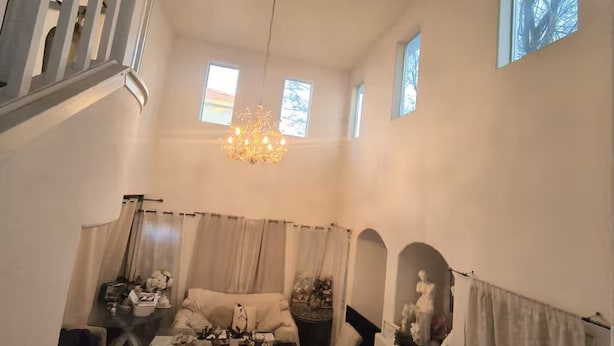 Tilava olohuone, jossa on kattokruunu, takka ja portaikko.