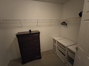 A small, dimly lit closet with a dark dresser, white shelves, and a hanging rack. - 1-bedroom bed & breakfast in delightful Las Vegas with AC (Las Vegas)