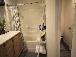 Ein Badezimmer mit Dusche, Toilette, Waschbecken und Ablage für Kosmetikartikel.