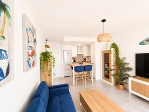 A modern living room with a blue sofa, wooden coffee table, and a TV on a wooden cabinet. - El Mirador del Sol . (Conil de la Frontera)