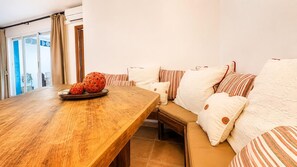 A cozy room with a wooden table, a cushioned seating area, and a view through a glass door. - Casa Vega Vera Playa | Primera Línea de Playa | Beachtfront luxury Apartment with garden (Vera Playa)