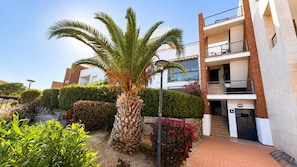 A multi-story building with a balcony, a palm tree, and a paved walkway. - Casa Vega Vera Playa | Primera Línea de Playa | Beachtfront luxury Apartment with garden (Vera Playa)