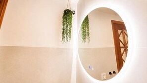 A room with a circular mirror, a hanging plant, and a wooden door. - Casa Vega Vera Playa | Primera Línea de Playa | Beachtfront luxury Apartment with garden (Vera Playa)