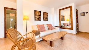 A living room with a sofa, a wooden coffee table, a wicker chair, and a floor lamp. - Vera Playa Beachtfront Apartment with garden & 4 Pools (Vera Playa)