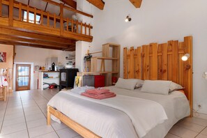 A bedroom with a wooden bed, a loft area with a wooden railing, and a white wall with a wooden panel design.