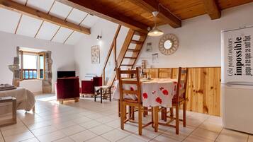 A spacious kitchen with wooden beams, a dining table with chairs, and a refrigerator.