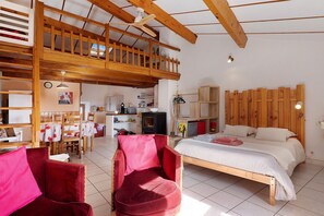 Ruime kamer met een vide, een bed met wit beddengoed en een eethoek met een tafel en stoelen.