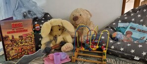 A room with a bed, a teddy bear, a book, and a toy.