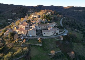 Ein Blick von oben auf ein historisches Dorf mit Steinbauten, kurvenreichen Straßen und umliegenden Hügeln.