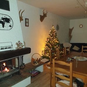 Uma sala de estar aconchegante com lareira, árvore de Natal e chifres de veado na parede.